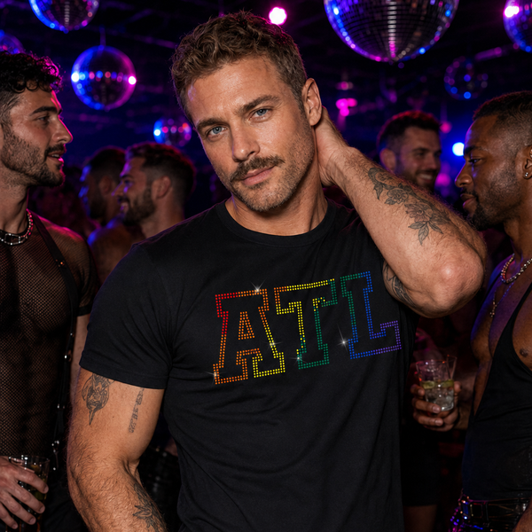 Man wearing a fitted black T-shirt with bold rainbow rhinestone "ATL" lettering at a gay nightclub. Atlanta Pride LGBTQ+ graphic tee for Pride festivals, nightlife, circuit parties, travel, and everyday statement fashion by Rico Starr