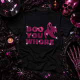 A black short-sleeve T-shirt laid flat with a pink rhinestone-style graphic reading 'BOO YOU WHORE' and a ghost silhouette by Rico Starr