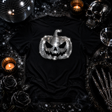 A black short-sleeve T-shirt laid flat with a large silver metallic disco-ball pumpkin graphic by Rico Starr