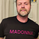 Man wearing a black t-shirt with 'MADONNA' in pink rhinestone letters by Rico Starr
