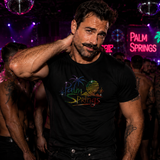 A man in a nightclub wearing a black t-shirt with a rainbow 'Palm Springs' graphic, surrounded by shirtless men under purple and pink party lights by Rico Starr