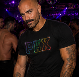 A muscular man with tattoos wearing a black t-shirt with 'PHX' in rainbow rhinestones, standing in a dimly lit nightclub with purple lighting by Rico. Starr