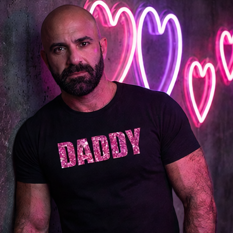 Man wearing a black t-shirt with 'DADDY' in pink letters against a neon heart background.