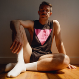 Rod Thomas of Bright Light Bright Light wearing a black shredder tank top featuring a pink glitter triangle Pride graphic. LGBTQ+ inspired sleeveless shirt celebrating gay pride, queer history, self-expression, and inclusive Pride fashion with a modern minimalist design by Rico Starr