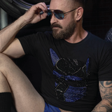 Man wearing a black t-shirt featuring a blue and black rhinestone pup mask graphic. LGBTQ+ fetish fashion inspired by pup play, leather culture, and gay nightlife, with sparkling crystal details, a fitted modern cut, and bold clubwear styling by Rico Starr