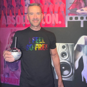 Man wearing black "I Feel So Free" rainbow rhinestone Pride t-shirt at a nightclub event by Rico Starr