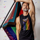 Male model wearing a black deep armhole tank top featuring a sparkling rhinestone Progress Pride flag design while by Rico Starr