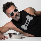 Silver fox male model wearing a black cut-off tank top with rhinestone “WOOF” dog bone graphic and white sunglasses beside a metal dog bowl by Rico Starr