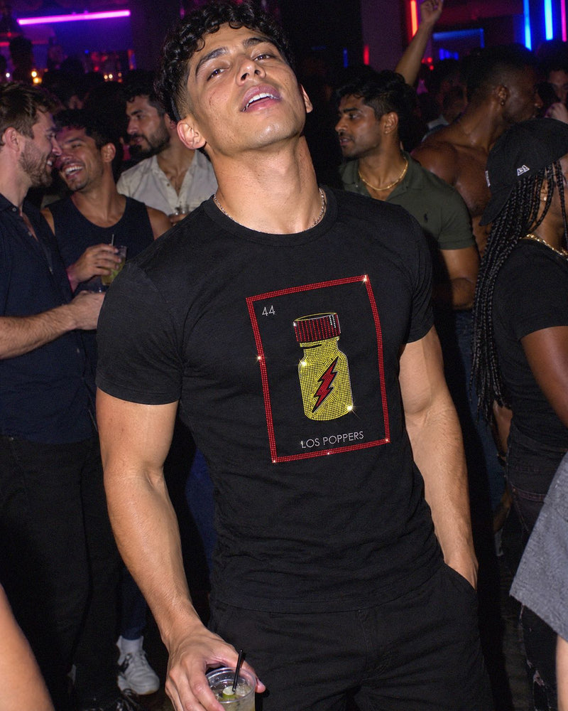A man at a party wearing the Los Poppers shirt